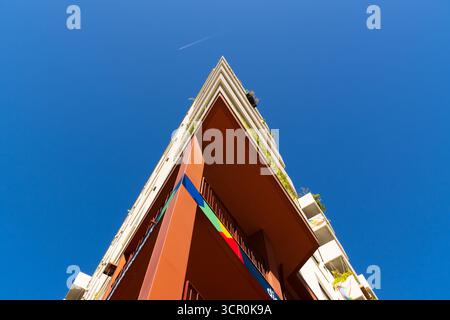 Minimalist modern residential building with white geometric facade and recessed windows against bright blue cloudy sky Stock Photo