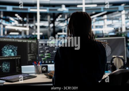 Data center technician uses AI visualization tool on computer to oversee automated repetitive tasks. Worker adapting server systems based on data analytics graphs using desktop PC Stock Photo