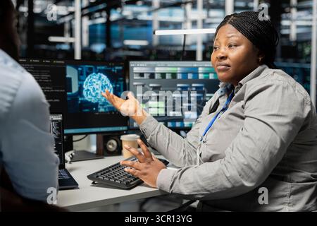 Server room engineering team doing brainstorming, using artificial intelligence to reduce downtime. Teamworking colleagues design and implement AI driven solutions for data center equipment Stock Photo