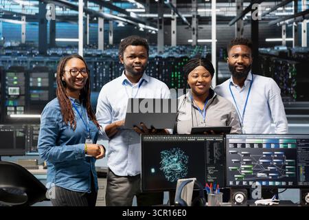 Portrait of smiling data center specialists using machine learning algorithms to analyze large datasets. Happy server farm coworkers using artificial intelligence to recognize facility data patterns Stock Photo