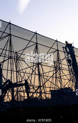 Construction site with protective netting and scaffolding at sunrise or sunset Stock Photo