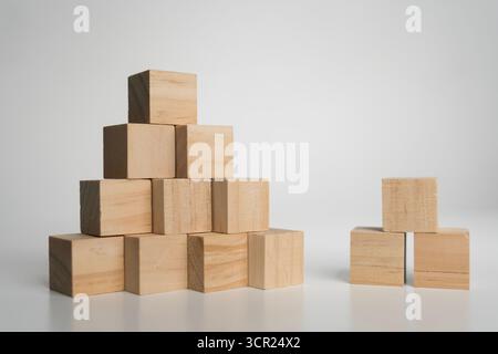 Natural wooden cubes forming large pyramid and small stack on white background, representing teamwork, growth, strategy, foundation, creativity, balan Stock Photo