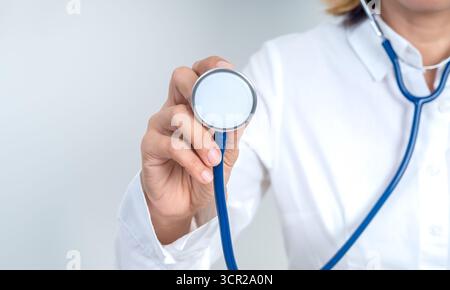 Doctor holding stethoscope for health checkup and medical examination on white background. Healthcare professional service, preventive care, diagnosis Stock Photo