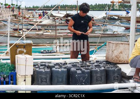A man preparing plastic containers for boat transport using a banca in Cebu, Philippines Stock Photo