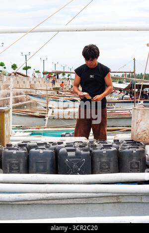 A man preparing plastic containers for boat transport using a banca in Cebu, Philippines Stock Photo