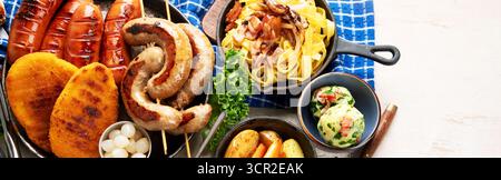 Various austrian dishes- schnitzel, sausages, potatoes, Knodel, salad and sauces on a light background. Top view. Panorama with copy space. Stock Photo