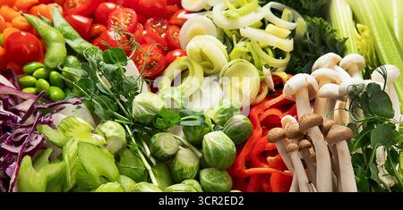 Variety of fresh chopped vegetables: carrots, cucumber, red bell pepper, tomato, salad, onion on a light background. Top view. Stock Photo