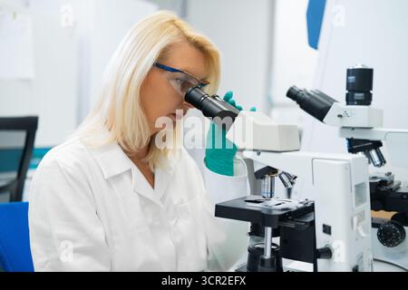 Young scientists conducting research investigations in a medical laboratory using a microscope. Stock Photo