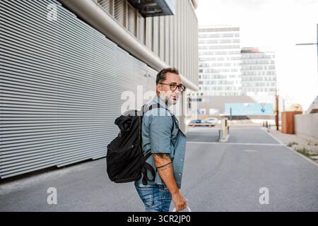 Handsome man with tattoos walking down the street. Stock Photo