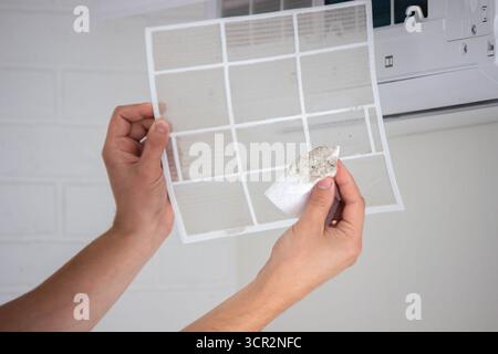 Air Conditioner Maintenance: Removing a Dirty Air Filter. Stock Photo