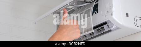 Maintenance Complete. Technician Installing Clean Air Filter in Air Conditioner. Stock Photo