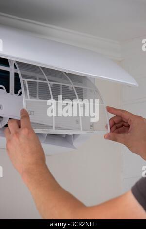 Maintenance Complete. Technician Installing Clean Air Filter in Air Conditioner. Stock Photo
