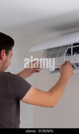 Maintenance Complete. Technician Installing Clean Air Filter in Air Conditioner. Stock Photo