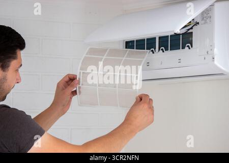 Air Conditioner Maintenance: Removing a Dirty Air Filter. Stock Photo