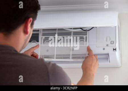 Maintenance Complete. Technician Installing Clean Air Filter in Air Conditioner. Stock Photo