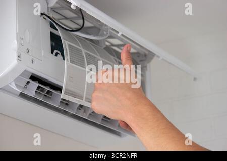 Maintenance Complete. Technician Installing Clean Air Filter in Air Conditioner. Stock Photo