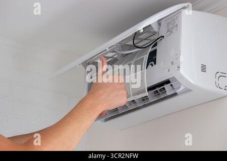 Maintenance Complete. Technician Installing Clean Air Filter in Air Conditioner. Stock Photo