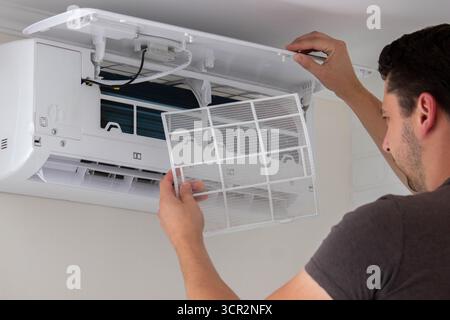 Maintenance Complete. Technician Installing Clean Air Filter in Air Conditioner. Stock Photo