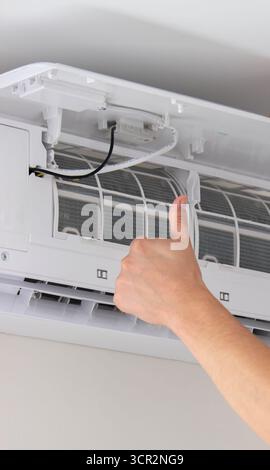 Maintenance Complete. Technician Installing Clean Air Filter in Air Conditioner. Stock Photo