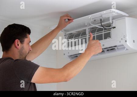 Maintenance Complete. Technician Installing Clean Air Filter in Air Conditioner. Stock Photo