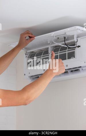 Maintenance Complete. Technician Installing Clean Air Filter in Air Conditioner. Stock Photo