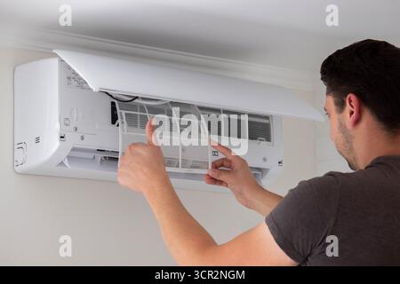Maintenance Complete. Technician Installing Clean Air Filter in Air Conditioner. Stock Photo