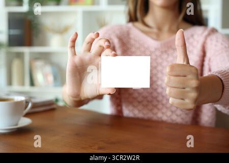 Close up of a woman hands showing business card gesturing thumb up at home Stock Photo