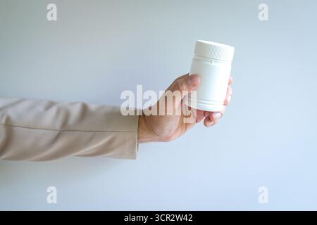 Person holding a white color bottle. Isolated on white background, close up view. Stock Photo
