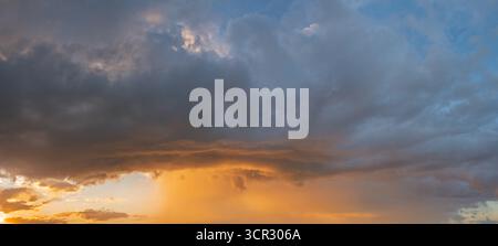 Cumulonimbus capillatus storm cloud illuminated by the setting sun Stock Photo