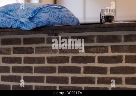 Folded blue towel resting on brown brick wall indoors with soft light. Stock Photo