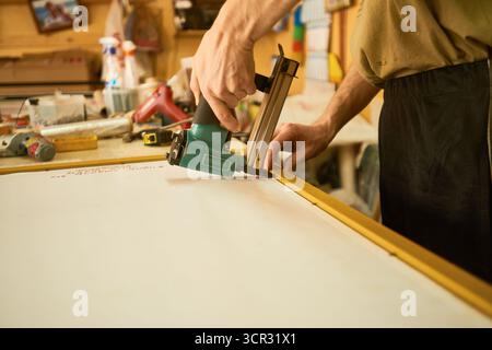 Man Assembling Wooden Frame Using Electric Stapler Stock Photo