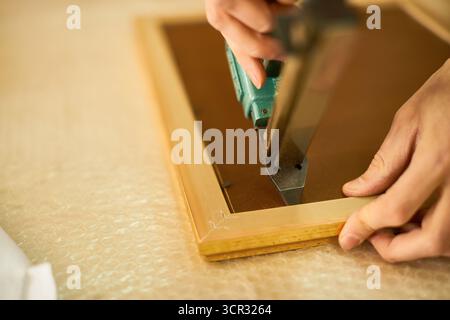 Man Assembling Wooden Frame Using Staple Gun Stock Photo