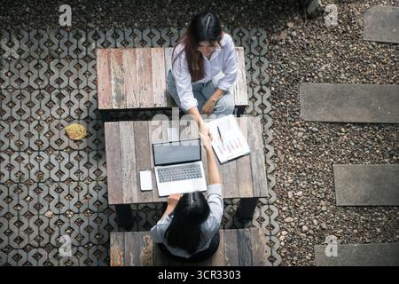 Top view of two businesswomen shaking hands over a desk. Stock Photo