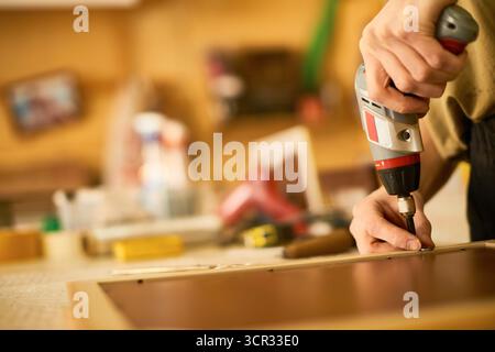 Man Assembling Furniture Using Electric Screwdriver Stock Photo