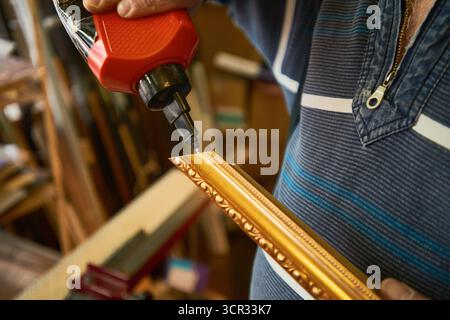 Man Assembling Ornate Frame Using Electric Screwdriver Stock Photo