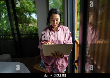 Happy young woman working remotely from home, enjoying a relaxed and comfortable atmosphere Stock Photo