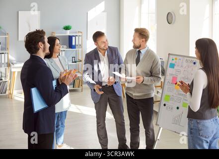 Cheerful business professionals discussing ideas and analyzing plans during team meeting in office. Stock Photo