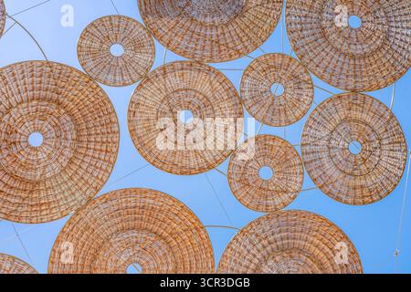 Abstract Background of Woven Wicker and Rattan Parasols Creating an Artistic Shade Canopy Over a Street. Interlocking Geometric Circles Stock Photo