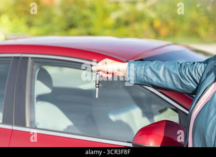 Female hand holds a car key. Woman's hand holding car keys. Close up. Unrecognizable driver holding key to new car in hand. Stock Photo