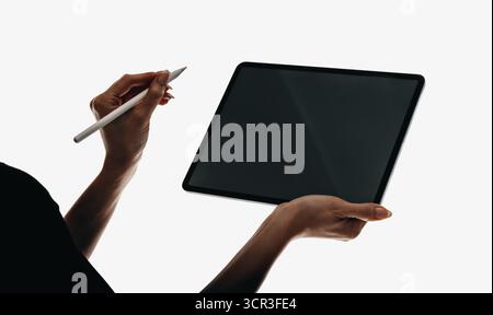 A close-up view of a person using a stylus with a digital tablet. The minimalistic composition shows the device's sleek design. The hands illustrate i Stock Photo