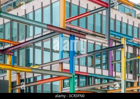 Abstract view of a contemporary office building facade framed by a chaotic structure of intersecting, painted steel beams creating a modern pattern Stock Photo