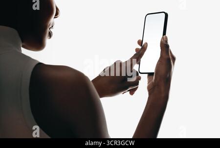Close-up of a woman swiping on a smartphone with blank screen, isolated on white background. Ideal for mobile app mockups, technology concepts, and mo Stock Photo