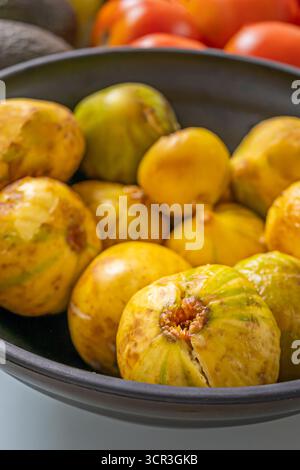 Still life with purple figs, green pears, ripe avocados, earthy potatoes, and orange nectarines creating a rainbow of colors on a pastel blue table Stock Photo