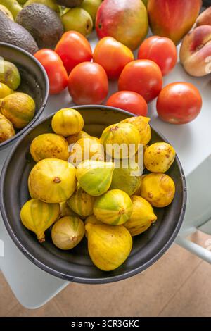 Photo composition where the velvety skin of the figs contrasts with the softness of the pears, avocados, potatoes, and nectarines on a light blue back Stock Photo