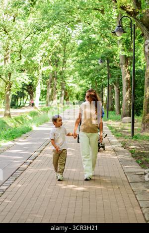Caucasian mother and son enjoy leisure time in park walking and talking, smiling laughing. Serene family connection. Stock Photo