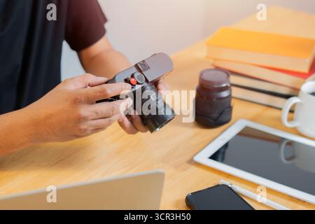 Photographer sitting on wooden table in office and checking shots. Selective focus. Stock Photo