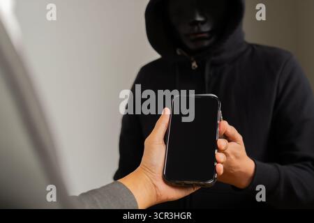 Phone Scammers, man in a mask receive information from employers by a phone, criminal network stealing data, hacker breaking into accounts, online saf Stock Photo