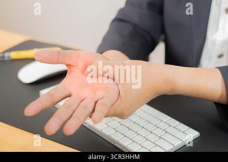 Close up employee man massage on his hand and palm for relief pain from hard working on the desktop table at home office. Stock Photo