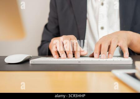 Closeup image of a business man's hands working and typing on computer keyboard on wooden table at office. Stock Photo