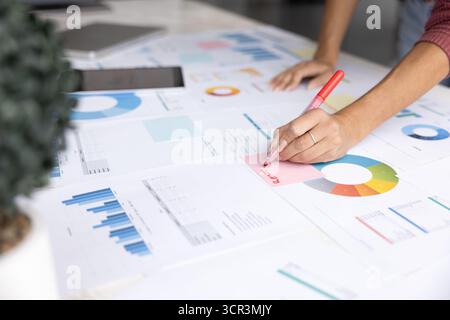 Professional woman writing on sticky note, close up Stock Photo
